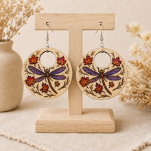 Cargar imagen en el visor de la galería, Autumn Wings hand-painted wooden earrings displayed front-facing on a light wood stand.