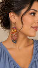 Cargar imagen en el visor de la galería, Model wearing a boho feather wooden earring with a muted denim-blue top, showing the approximately 3-inch lightweight statement earring at a natural scale.