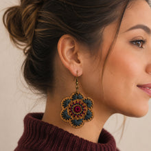 Cargar imagen en el visor de la galería, Crimson Roots embroidered wooden earring worn with a burgundy sweater, showing its size and scale.