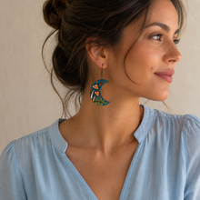 Cargar imagen en el visor de la galería, Enchanted Forest Moon wooden earring shown at realistic scale on a model wearing a soft powder-blue blouse.