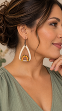 Cargar imagen en el visor de la galería, Model wearing the lightweight Sunflower Blessed wooden earring with a soft sage-green blouse, showing realistic scale and gunmetal-tone hook.