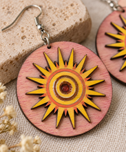 Cargar imagen en el visor de la galería, Close-up of Sunheart wooden earring showing natural wood grain, layered laser-cut sun, hand-painted details, dark cut edges, and resin accents