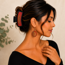 Cargar imagen en el visor de la galería, Model wearing the Tribal Feather wooden earrings with the matching large black hair clip and a simple black top.