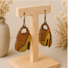 Cargar imagen en el visor de la galería, Angled view of Bag &amp; Heels 3D wooden earrings on a light wood stand, showing the layered construction.

