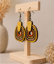 Cargar imagen en el visor de la galería, Angled view of Earth Echoes hand-painted wooden earrings on a light wood stand.
