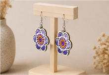 Cargar imagen en el visor de la galería, Angled view of Lavender Bloom hand-embroidered wooden earrings on a light wood stand.
