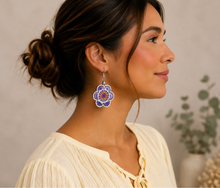Cargar imagen en el visor de la galería, Model wearing Lavender Bloom hand-embroidered wooden earrings with a soft warm ivory blouse.
