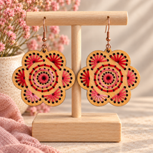 Cargar imagen en el visor de la galería, Natural Splendor hand-embroidered wooden flower earrings in red and pink on a light wood stand with bronze-tone hooks
