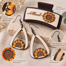 Cargar imagen en el visor de la galería, Detail view of the Sunflower Blessed set showing layered hand-painted sunflowers, laser engraving, natural wood grain, gunmetal-tone hooks, and the engraved Blessed hair clip.
