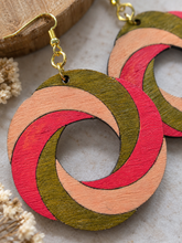 Cargar imagen en el visor de la galería, Close-up of SunTwist Joy wooden earrings showing visible wood grain, hand-painted brushstrokes, coral, peach and olive colors, and gold-tone hooks
